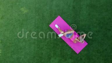 俯视图年轻运动女子在草地上表演扭扭动作